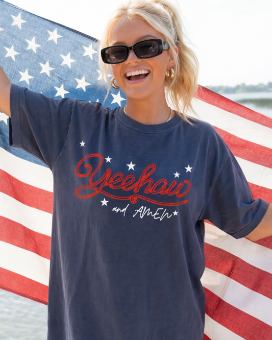 Woman holding USA flag wearing patriotic summer 4th of July inspired Yeehaw and Amen tee