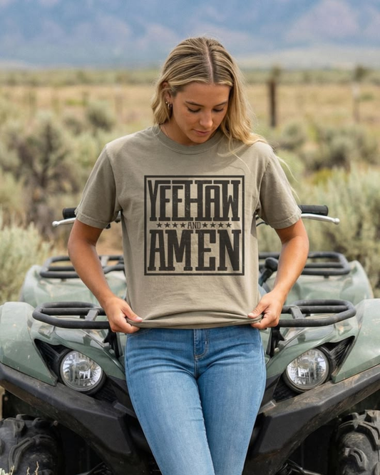 Woman wearing a Yeehaw and Amen Christian western graphic t-shirt sitting on an ATV in a desert landscape, styled with denim for a cowgirl outfit