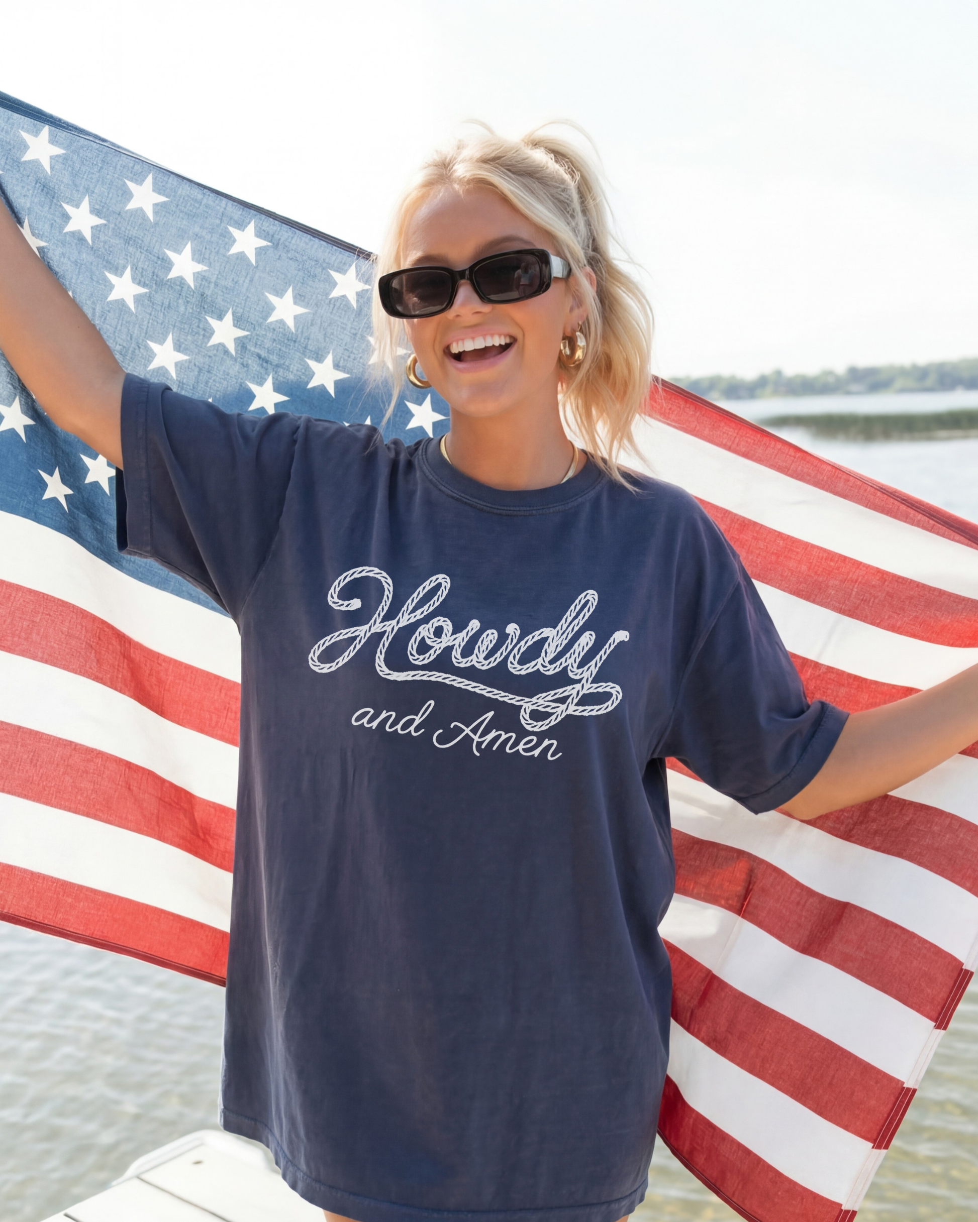 Patriotic woman wearing Howdy and Amen Tee hold up the USA flag