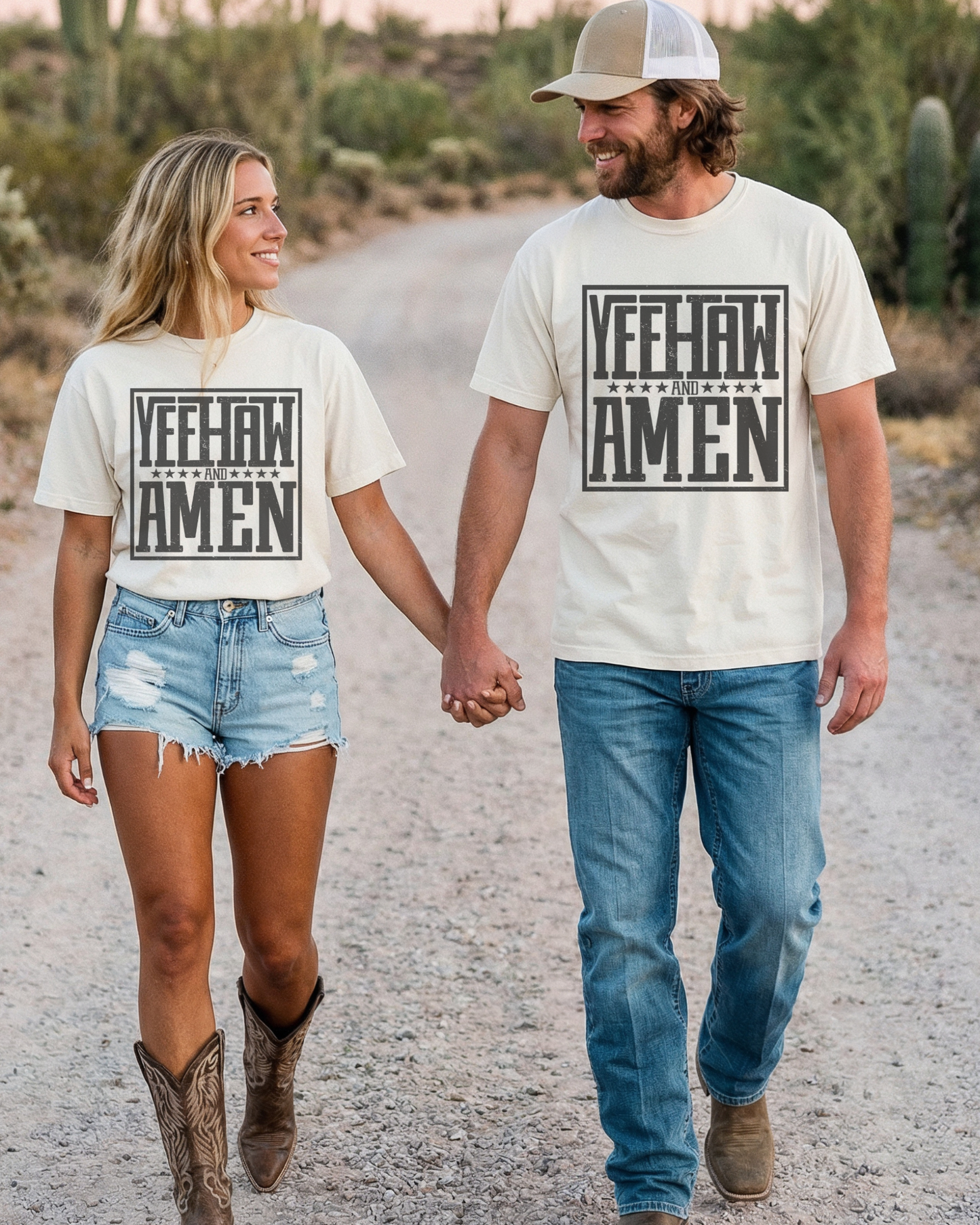 Couple walking hand in hand on a desert road wearing matching “Yeehaw and Amen” Christian western graphic t-shirts, styled with denim and cowboy boots for a faith-inspired cowgirl and cowboy outfit