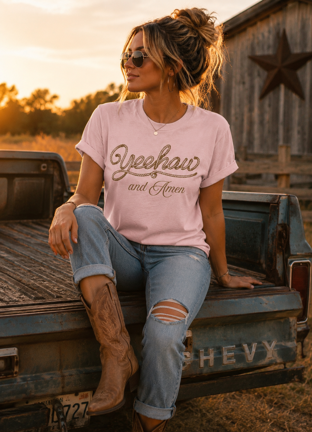 Women sitting on truck tailgate with barn in background wearing Pink western Faith tee Yeehaw and Amen